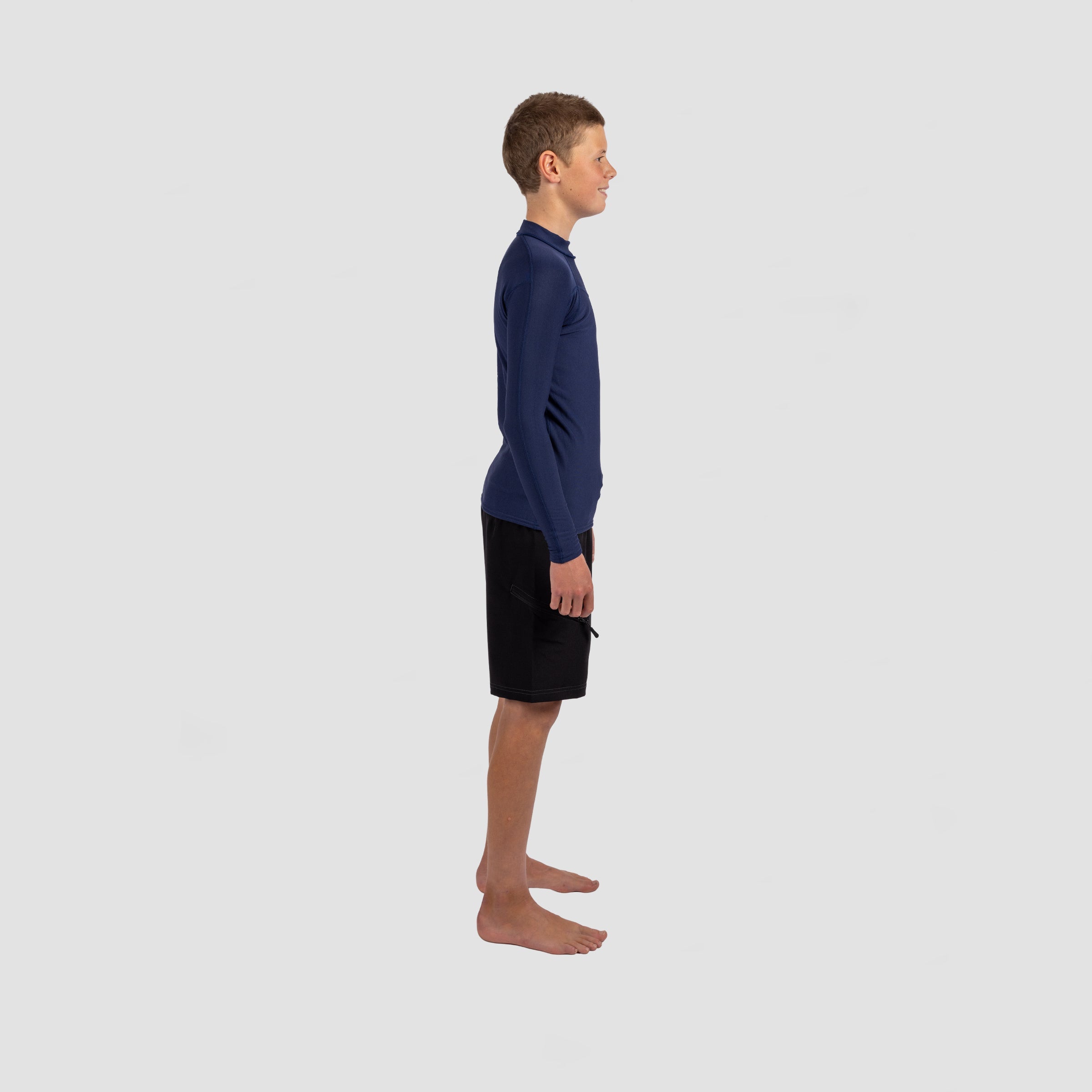 Side view — youth in Shark Eyes thermal rash vest in cold water — surfing