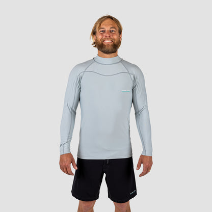 Man wearing a light gray long-sleeve Rash vest and black shark eyes instinct boardshorts on a light grey background