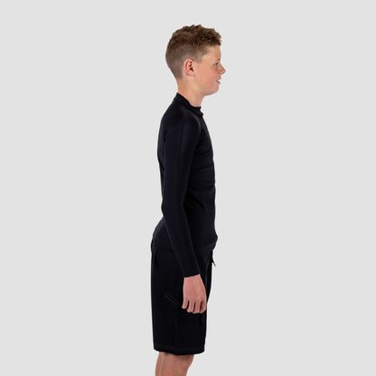 Boy wearing a black long-sleeve rash rest and shorts on a light gray background