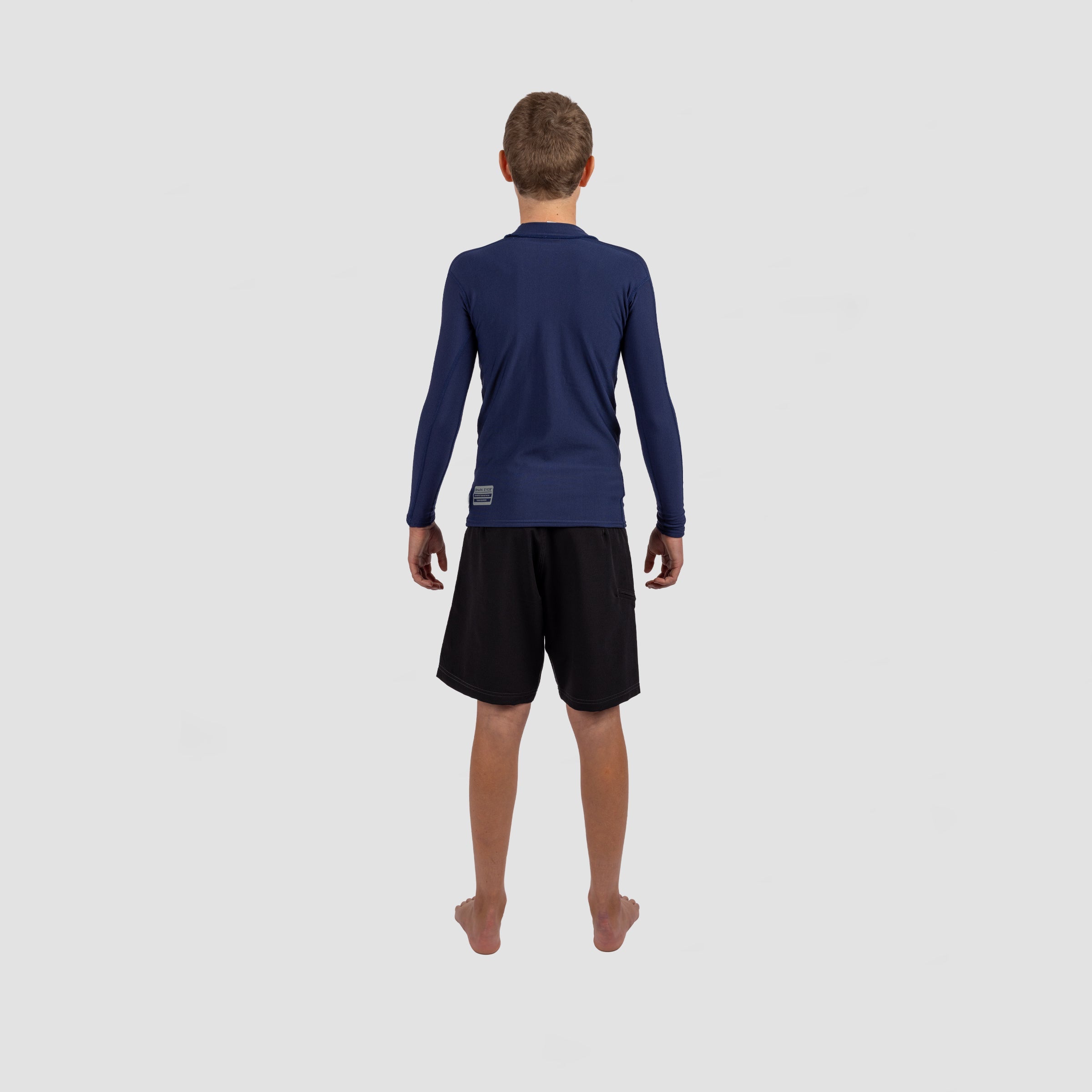 Youth in Shark Eyes thermal rash vest, back view — cold water surfing